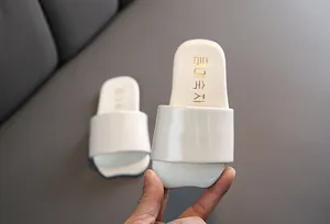 Primer plano de chanclas infantiles crema con detalles en texto coreano oro