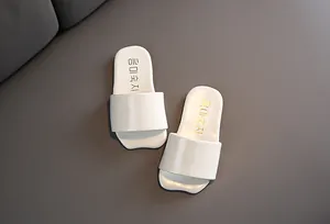Vista superior de chanclas blancas minimalistas para niños sobre fondo gris.
