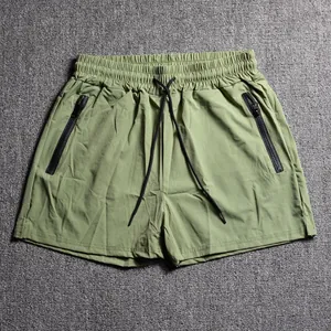 Men's olive green sports shorts with zipper pockets and drawstring waist detail