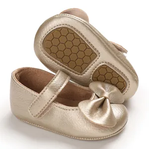 Gros plan de chaussures de princesse pour bébé dorées avec nœud et semelle souple