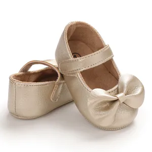 Vue détaillée de chaussures de marche dorées pour bébé avec semelle souple et grand nœud
