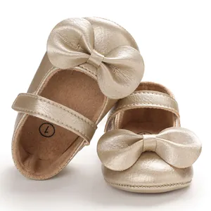 Détail de chaussures de princesse dorées pour bébé avec grand nœud et texture métallique