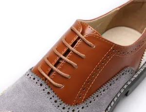 Détail macro de chaussures Richelieu bicolores en cuir marron et en daim gris texturé