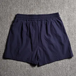 Back view of navy blue men's athletic shorts laid flat on a grey textured surface