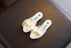 Close-up of decorative mesh bows and colorful beads on white girls' princess slippers.
