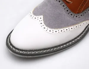 Gros plan détaillé montrant les coutures brogue sur une chaussure en cuir bicolore