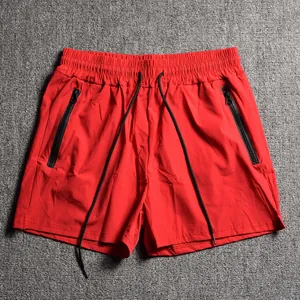 Detailed view of red men's sports shorts featuring black zipper pockets and drawstring.