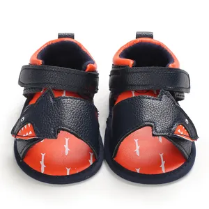 Front view of baby walking sandals with cute cartoon shark design in navy and orange