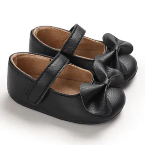 Gros plan sur les chaussures de marche noires pour bébé fille avec un nœud élégant