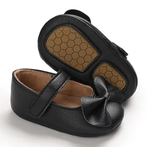 Vue détaillée de chaussures bébé noires avec semelles en caoutchouc souple et nœud