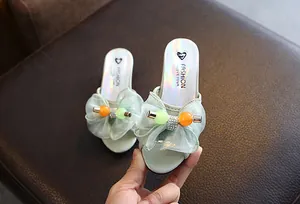 Macro detail of mint green girl slippers featuring a mesh bow and colorful beads