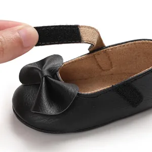 Gros plan sur la bride velcro ajustable d'une chaussure de bébé noire avec nœud