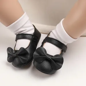 Gros plan de chaussures de princesse noires pour bébé avec un grand nœud et une semelle souple