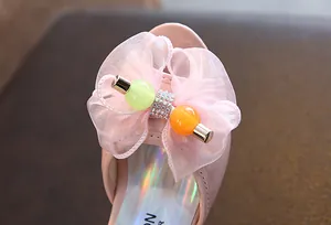 Close-up of pink organza bow with colorful beads and rhinestones on girl's shoe