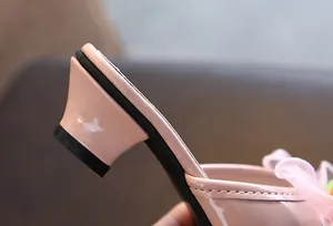 Detailed macro shot of the pink patent leather block heel on girls' stylish slippers