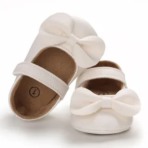 Détail de chaussures de princesse pour bébé fille blanches avec gros nœud et semelle souple