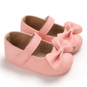 Détail de chaussures de princesse roses pour bébé fille avec un grand nœud et semelle souple.