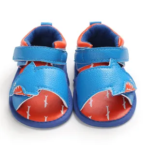Close-up front view of cute blue cartoon shark baby sandals with soft soles and straps.