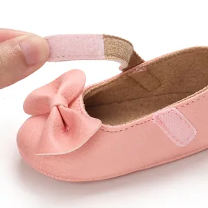 Gros plan détaillé de chaussure bébé fille rose avec nœud et bride à fermeture velcro souple