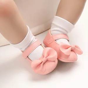 Gros plan de chaussures bébé roses avec un grand nœud décoratif et une semelle souple