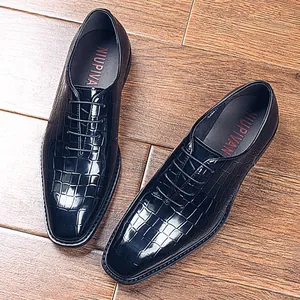 Elegante zwarte herenschoenen met krokodillenreliëf op een klassieke houten vloer