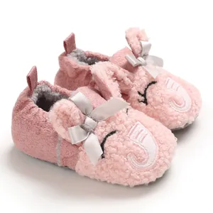Detalle de zapatos de sherpa rosa para bebé con bordado de elefante y lazo plateado