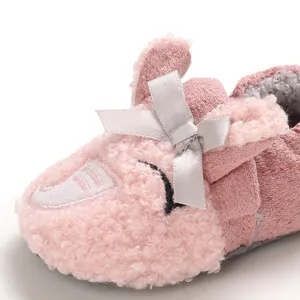 Detalle de zapatos de bebé rosa afelpados con lazo plateado y forro suave para caminar