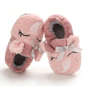 Primer plano de patucos rosa suaves para bebé con cara de dibujos y detalle lazo