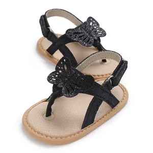 Detailed view of black baby sandals with butterfly motif and soft tan sole.
