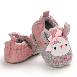 Detalle de los zapatos de peluche para bebé en rosa y gris con diseño de conejito.