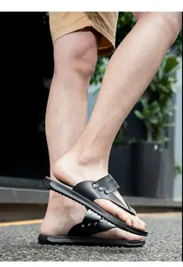 Detailed shot of black flat thong sandals featuring stylish metal rivets on street