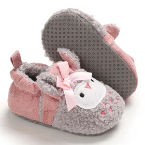 Vista detallada de zapatos de peluche rosa y gris con cara de cordero y un lazo