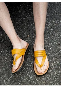 Top view outdoor detail shot of yellow thong sandals with rivet accents on asphalt