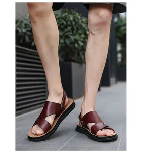 Detailed view of men's casual brown leather sandals worn outdoors on a street pavement.