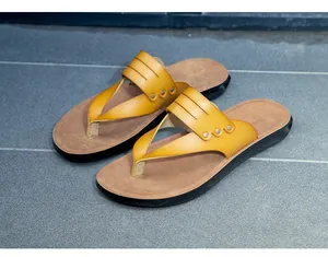 Detailed view of yellow faux leather flip flops with metal studs and textured soles