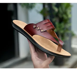 Close-up view of burgundy leather flat flip flops featuring metallic stud details