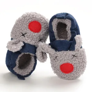 Detalle de zapatos de bebé en forro polar Sherpa gris con un diseño de cara de dibujos animados