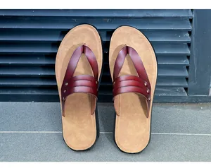 Overhead detail view of reddish-brown leather thong sandals featuring metal rivets.