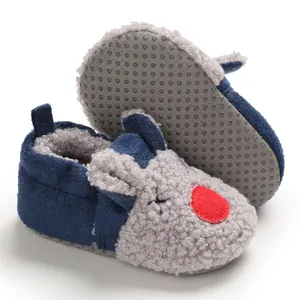 Detalle de zapatos de felpa para bebé con suela blanda antideslizante y diseño de dibujos.