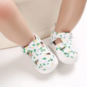 Close-up van witte baby loopschoentjes met groene bladprint en zachte ademende zool