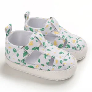 Close-up van witte baby sandalen met bladprint en klittenbandsluiting voor peuters