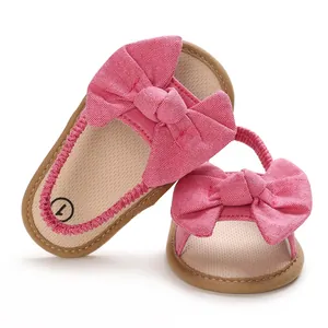 Detalle de sandalias rosas para bebé con lazo decorativo grande y suela blanda
