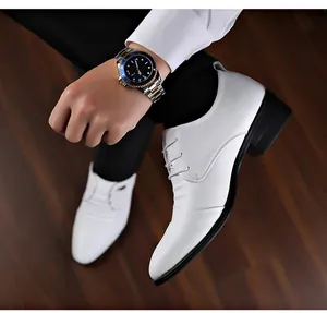 Primo piano di scarpe stringate bianche da uomo con rialzo interno su parquet