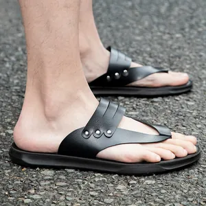 Black flat flip-flop beach sandals with silver stud accents shown on asphalt ground