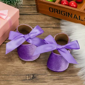 Detailed macro view of purple velvet baby princess shoes with a large satin ribbon bow