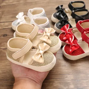 Macro view of glittery baby princess shoes with bows in gold, red, black, and silver.