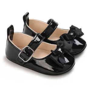 Close-up detail of black patent leather infant shoes with elegant bow and silver buckle