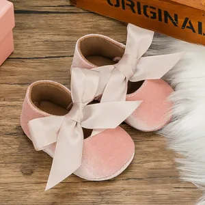 Detailed macro view of soft pink velvet baby princess shoes with large satin ribbon bow