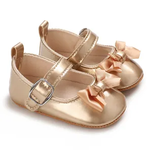 Detail view of golden baby girl princess shoes featuring a silk bow and adjustable buckle