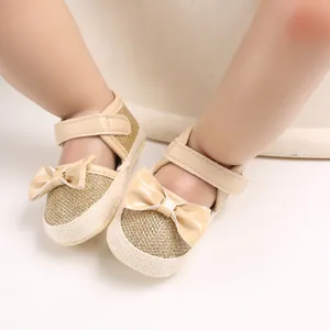 Close-up detail of gold glitter baby princess shoes with cream bows and soft soles